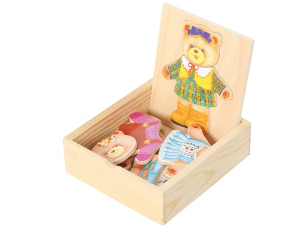 Holzspielzeug mit einem Bären und farbenfrohen Anziehsachen in einer Holzbox.